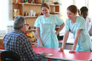 Deux professionnelles de la Clinique Le Castelet accompagnant un patient assis lors d'un échange autour d'une table. (® SAAM-fabrice Chort)